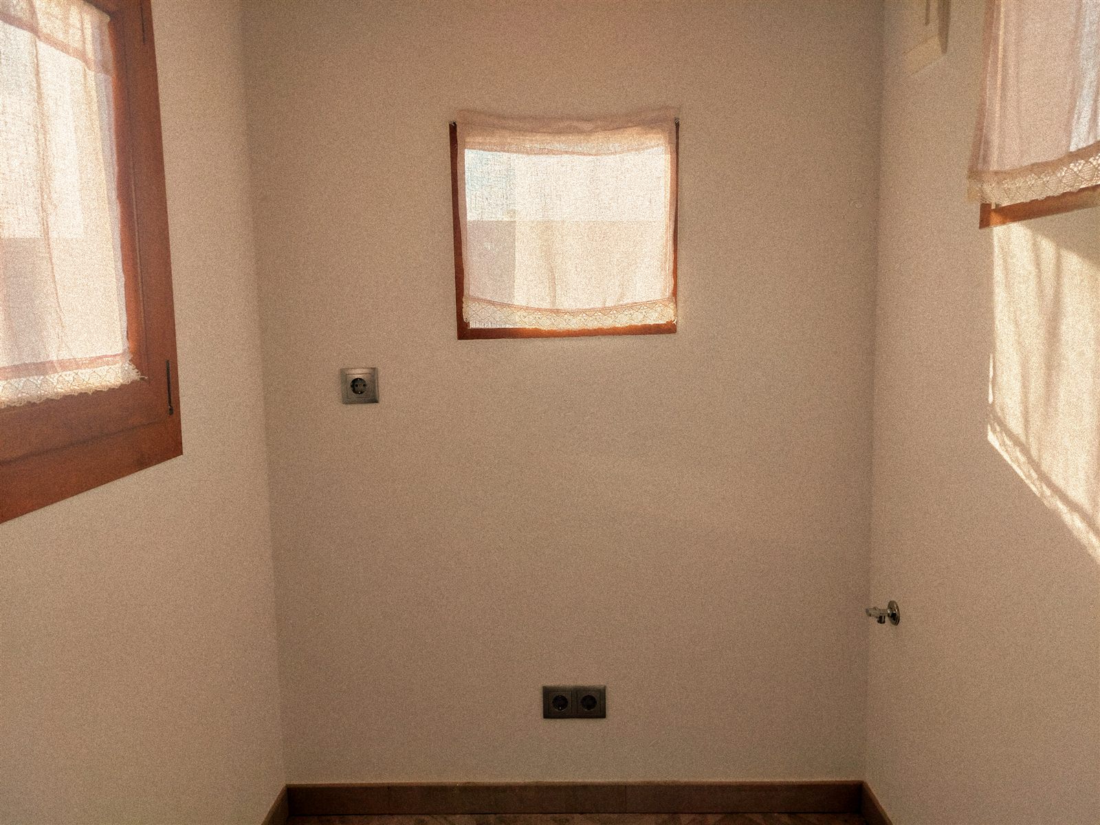 Interior de Naixent amb tres finestres de fusta i cortines